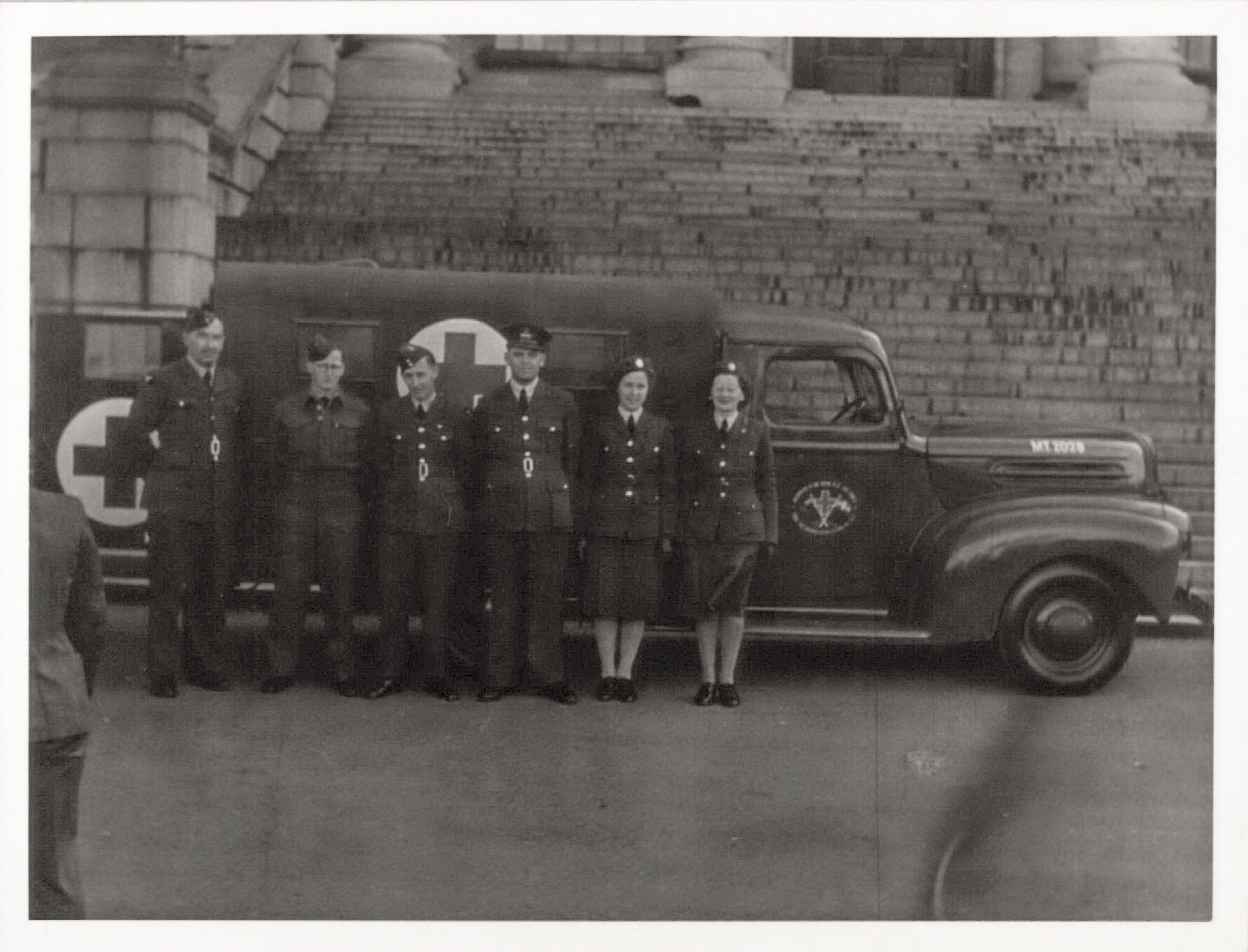 Representatives of Danes in service in New Zealand in front of the ambulance. From right to left: Mr. Peter Hansen, Mr. Kaj Mortensen, Mr. Knud Graae, Mr. Arne Møller, ambulance driver Mrs. Andersen, and Mrs. A. Hadrup.