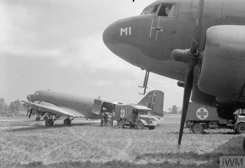 A casualty from the fighting in Normandy is loaded from an Army ambulance into one of the Douglas Dakota Mark IIIs of No. 46 Group at B2/Bazenville, Normandy, for evacuation to the United Kingdom.