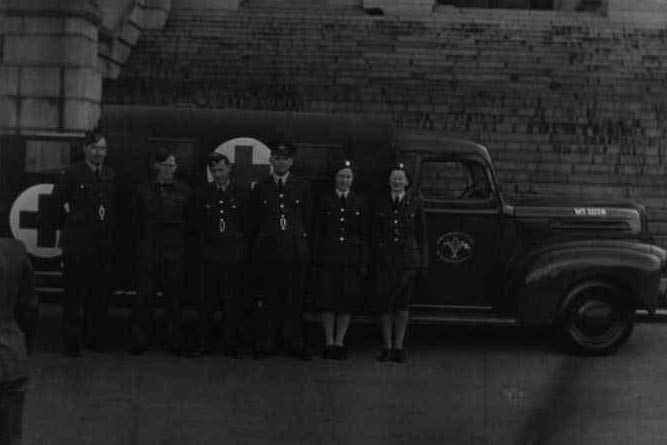 Representatives of Danes in service in New Zealand in front of the ambulance. From right to left: Mr. Peter Hansen, Mr. Kaj Mortensen, Mr. Knud Graae, Mr. Arne Møller, ambulance driver Mrs. Andersen, and Mrs. A. Hadrup.